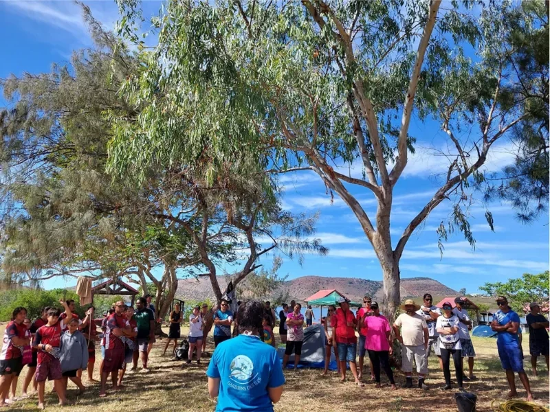 Un membre de l’association échange avec un groupe réuni sous les arbres